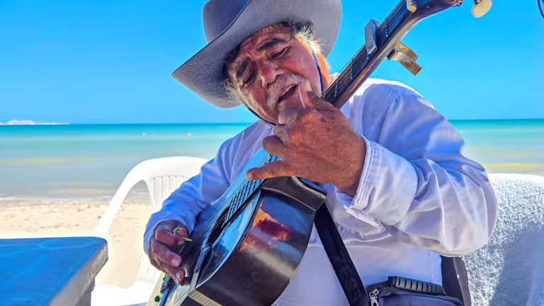 Gitarrist som spelar tranditionella visor på stranden i Yucatán
